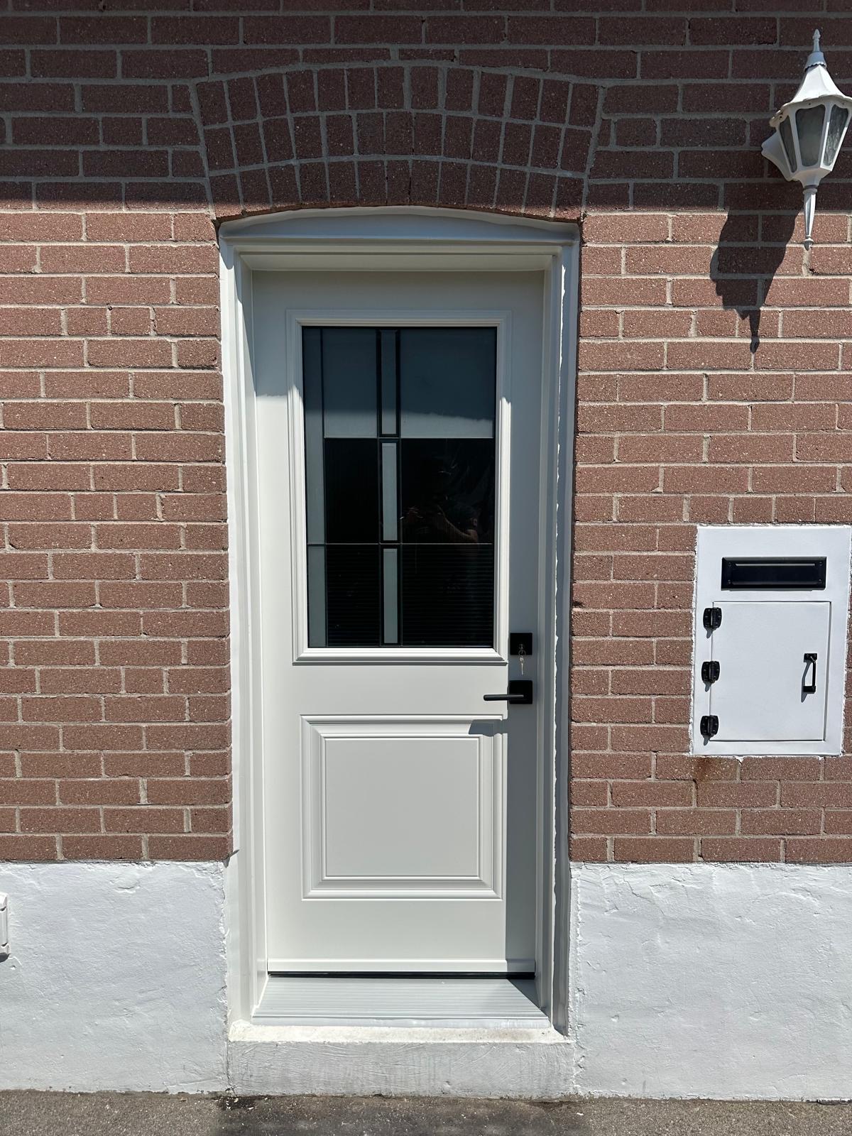 White entry door with decorative glass on a brick home